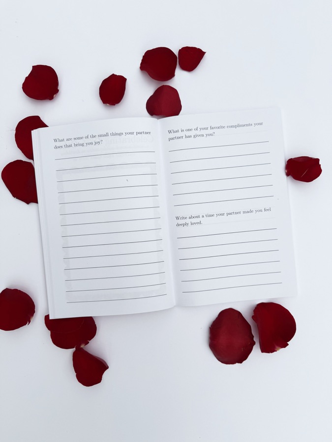 Open pages of the guided love story journal surrounded by rose petals
